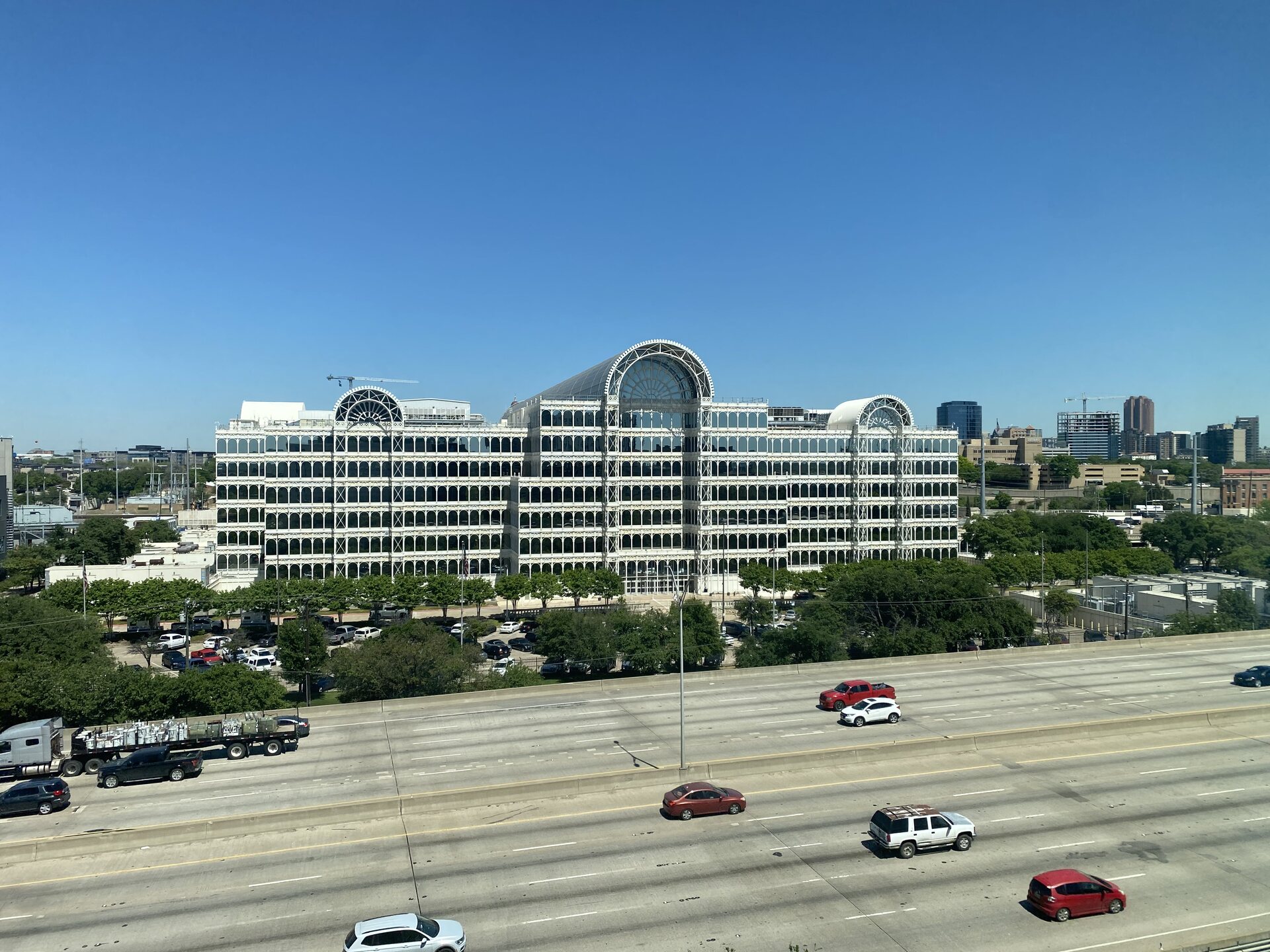 Daytime exterior of the Equinix Infomart Dallas data center beside Interstate 35E, with the Dallas skyline behind it.